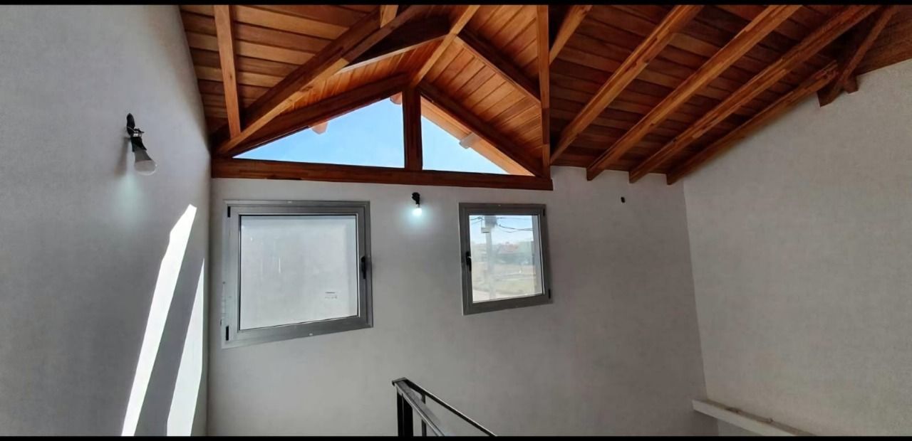 Vista interior con techo de madera, ventanas y paredes blancas.