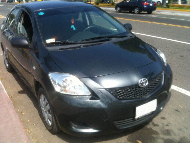 Sedán Toyota negro estacionado en una calle, vista frontal en ángulo.