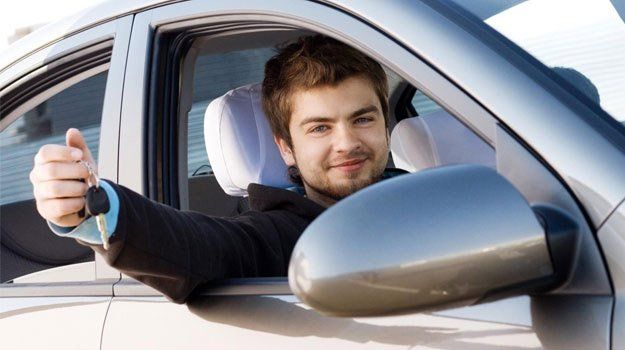 Conductor sonriente en un coche levantando el pulgar por la ventanilla abierta.