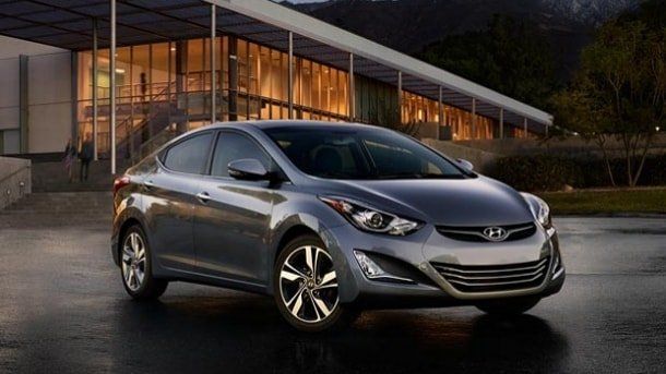 Un sedán plateado estacionado frente a un edificio moderno por la noche.