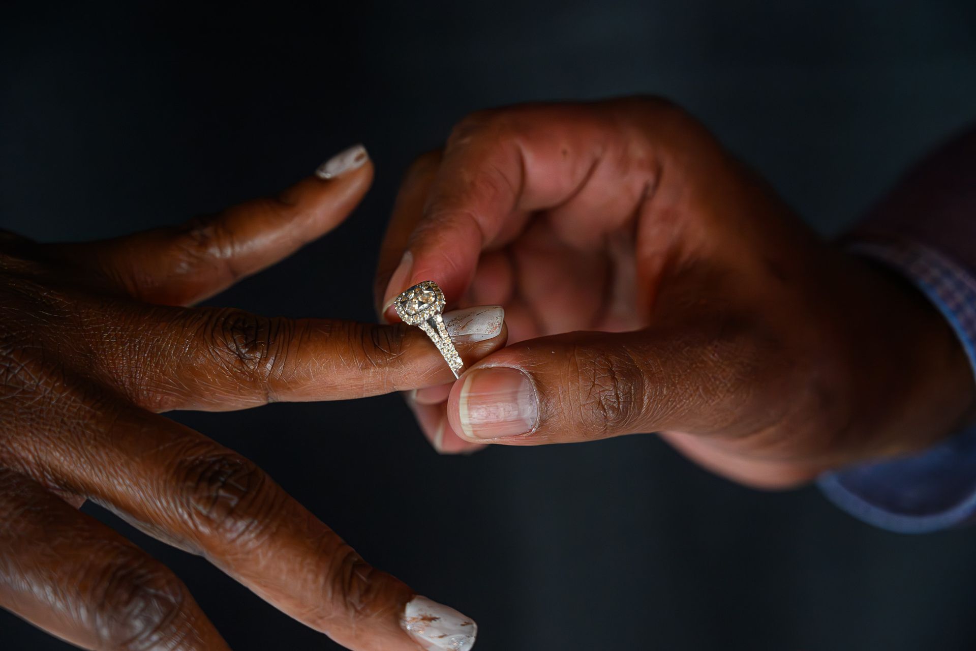 Person placing diamond ring on another person's finger.