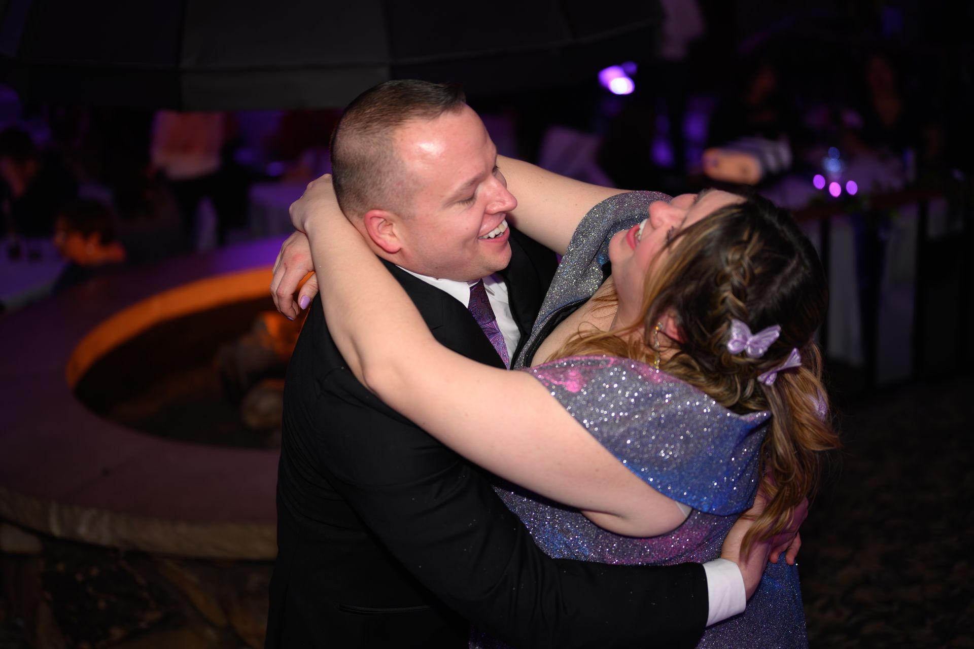 Couple embracing and laughing while dancing at an event.