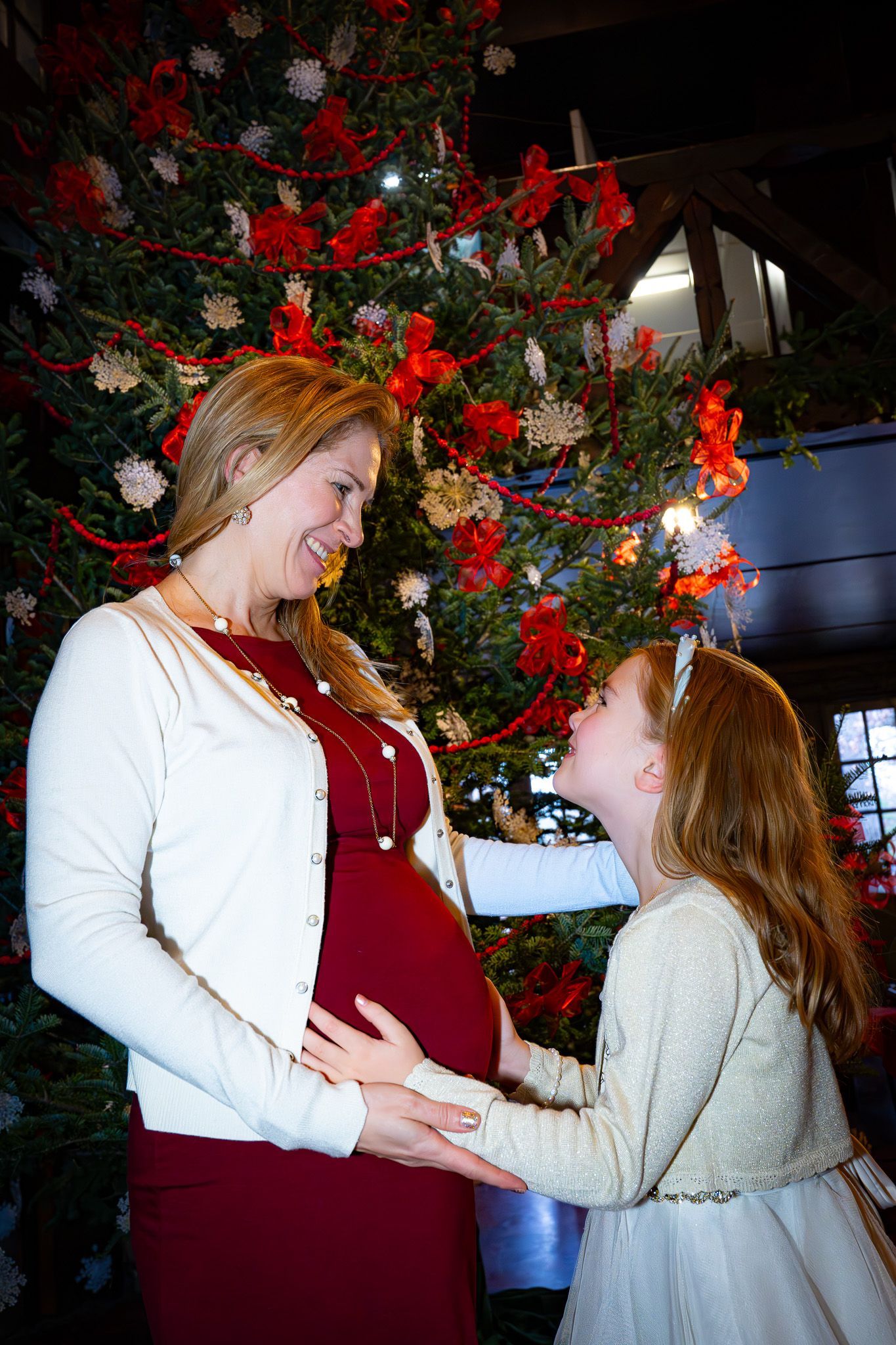 Pregnant woman and child looking at each other, Christmas tree in the background.