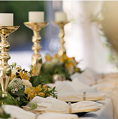 Elegant table setting with gold candle holders, flowers, and folded napkins.