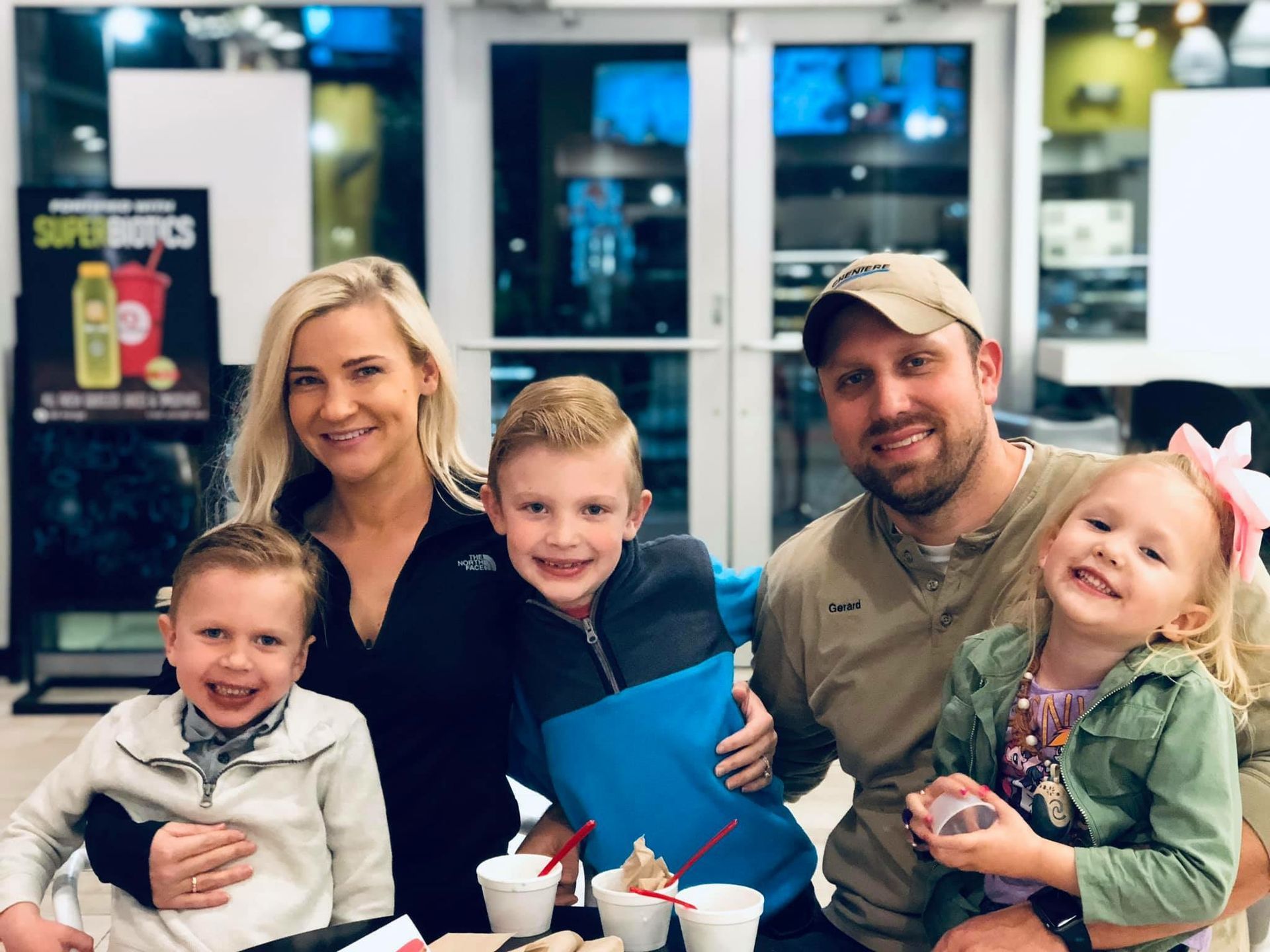 Family smiling at a restaurant table with desserts and drinks