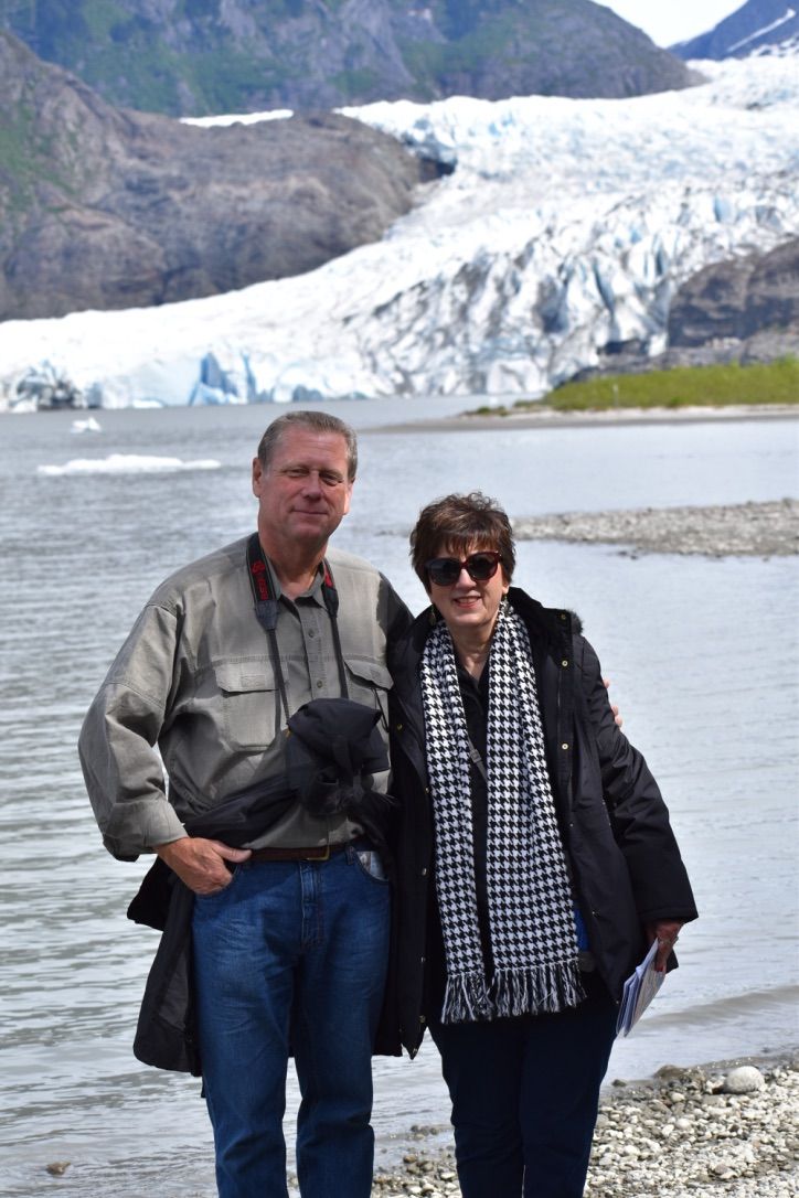 Couple posing by a lake with a glacier and mountains in the background