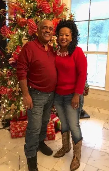 Couple in red tops posing by a decorated Christmas tree indoors