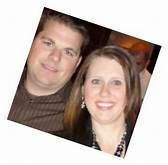 Two people smiling in a tilted snapshot, standing close together indoors.