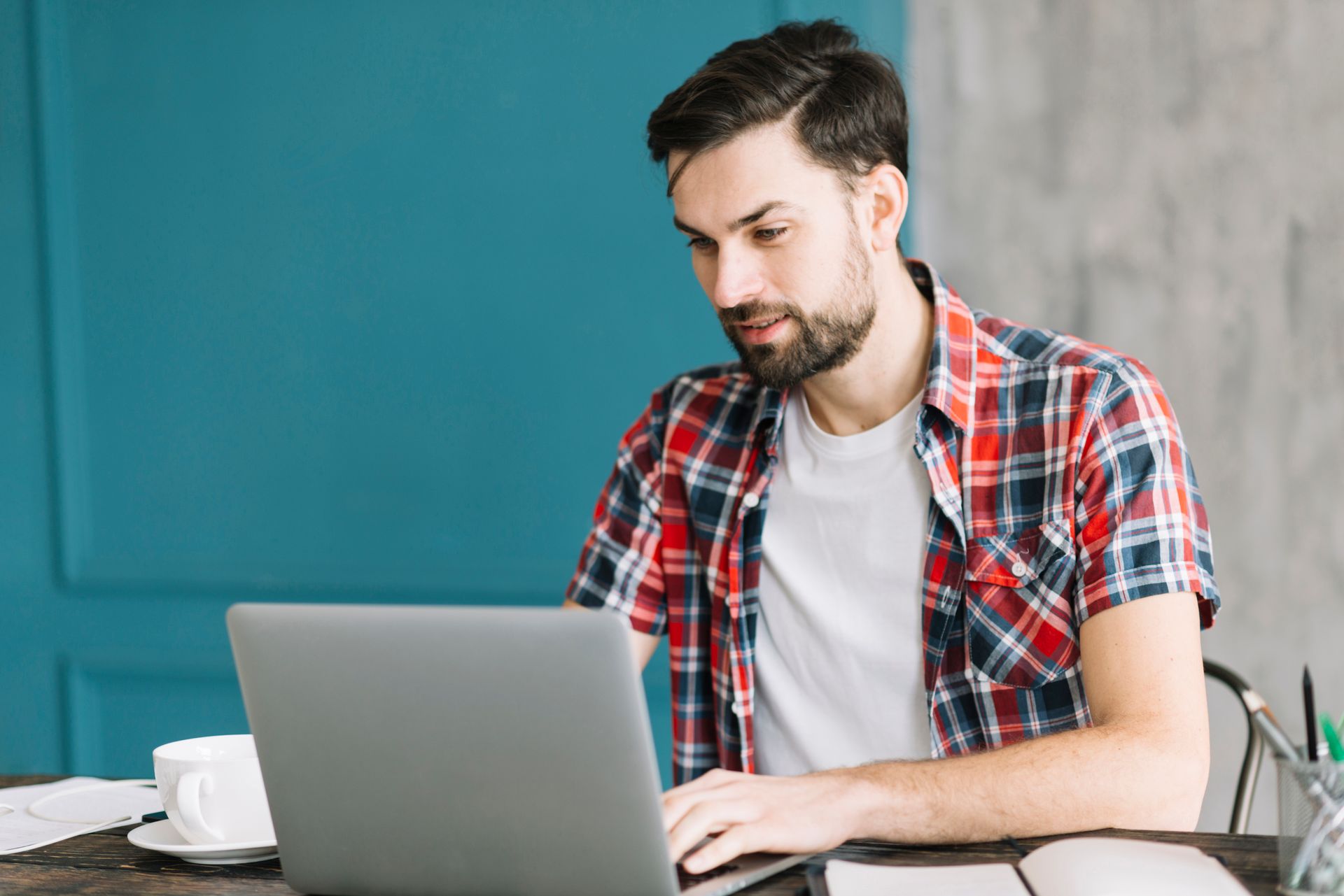 A man is sitting at a table using a laptop computer.