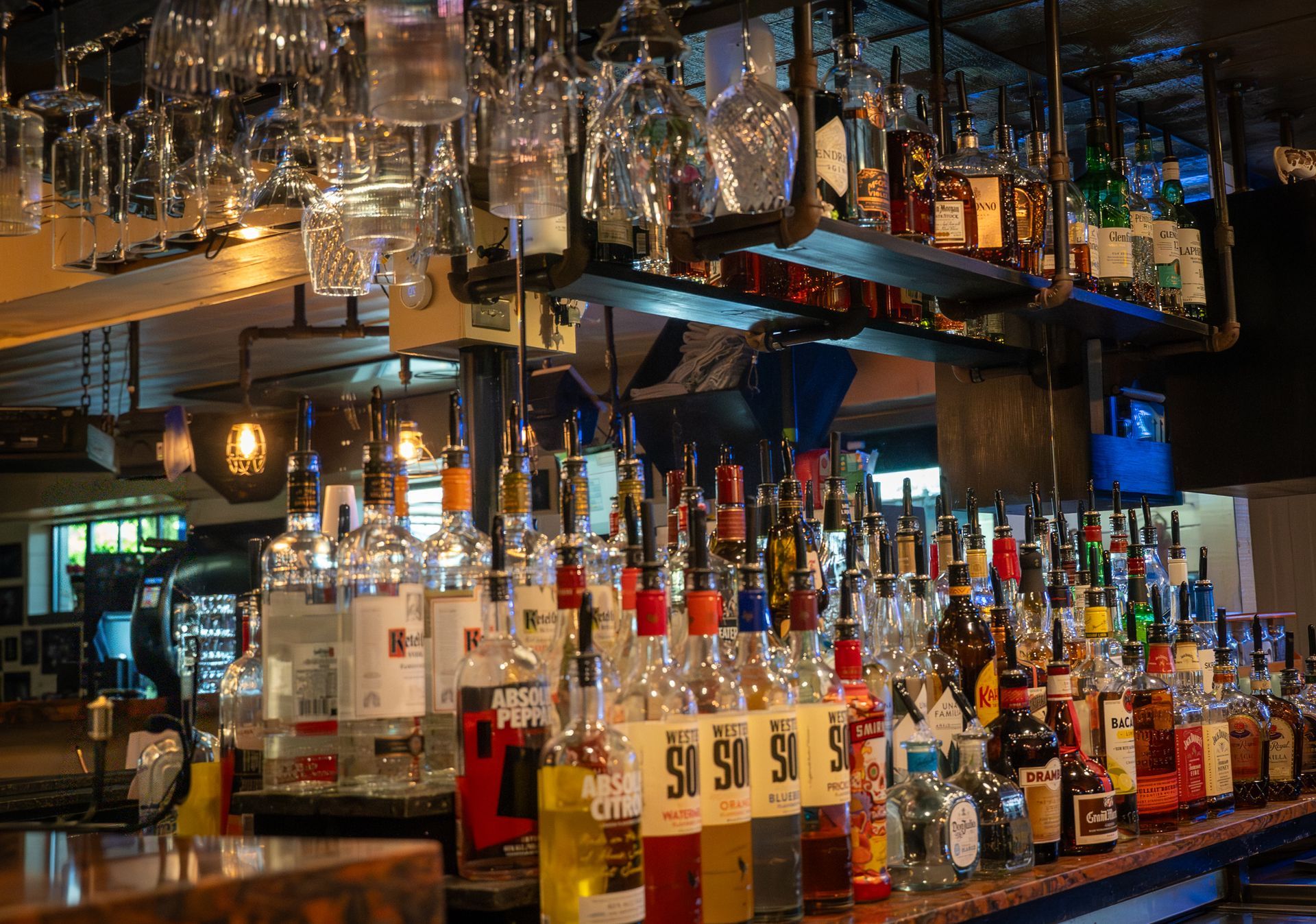 Bar interior with shelves of liquor bottles and hanging glassware.