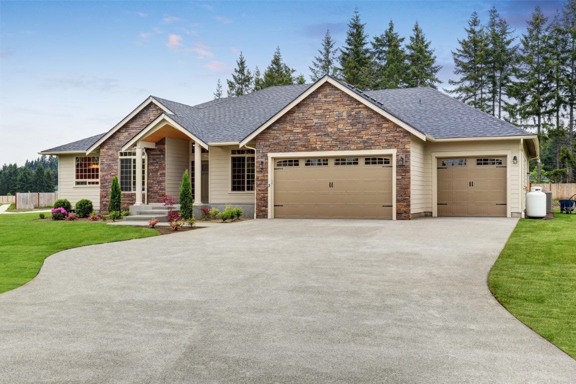 Single-story brick suburban house with a wide driveway, garage, and manicured lawn