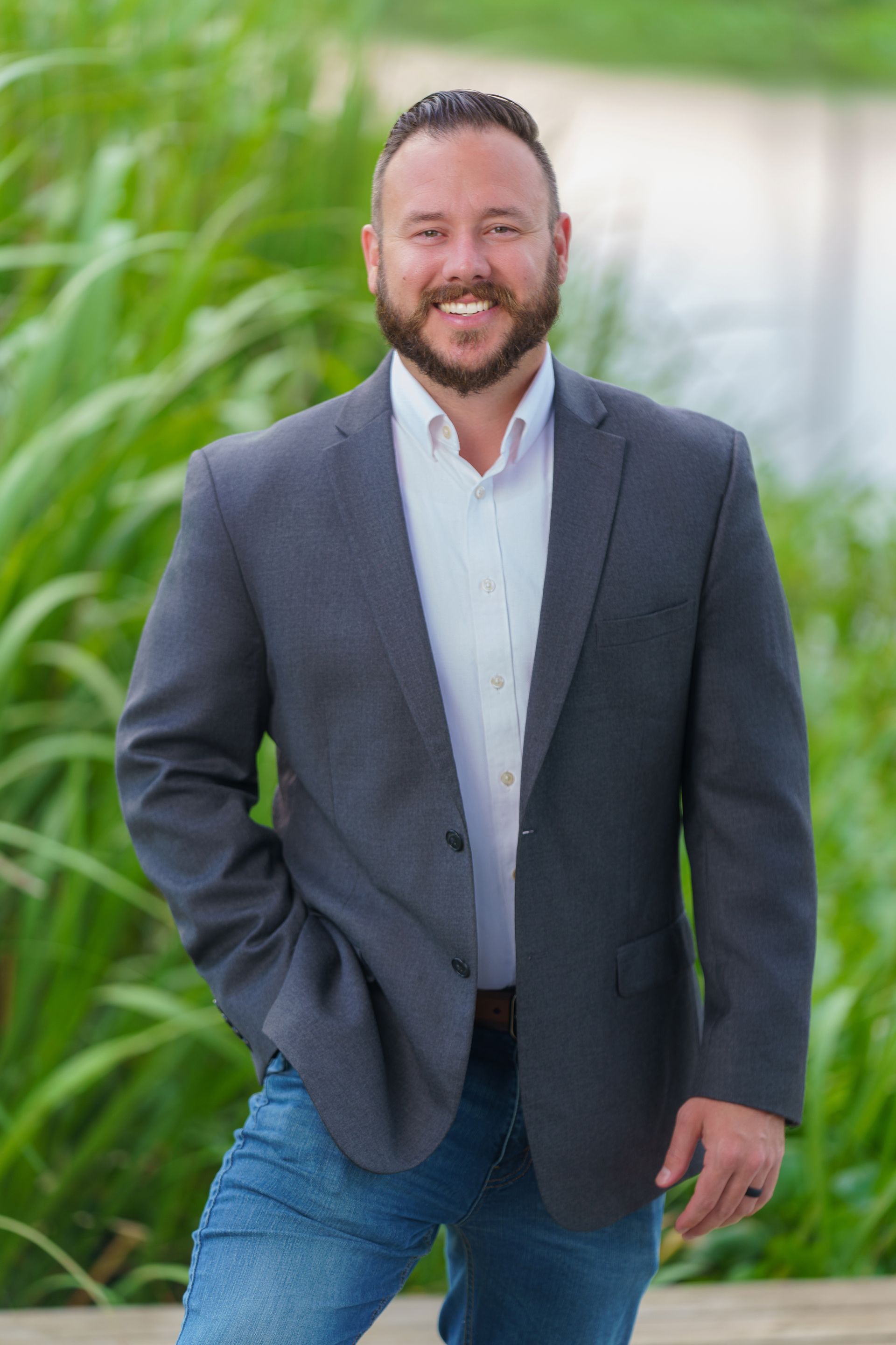 A man in a suit and jeans is standing with his hands in his pockets.