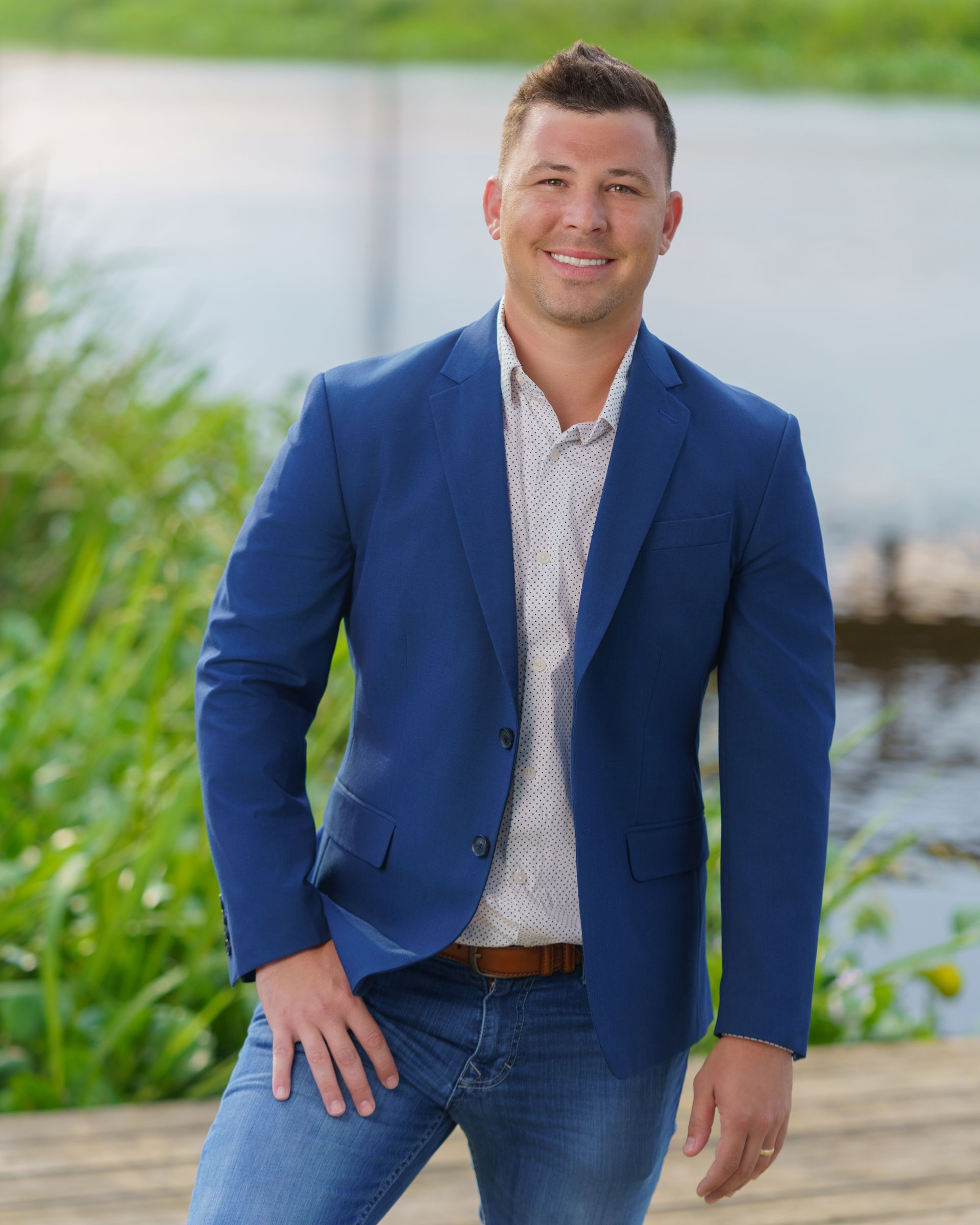 A man in a blue jacket and jeans is standing on a dock.