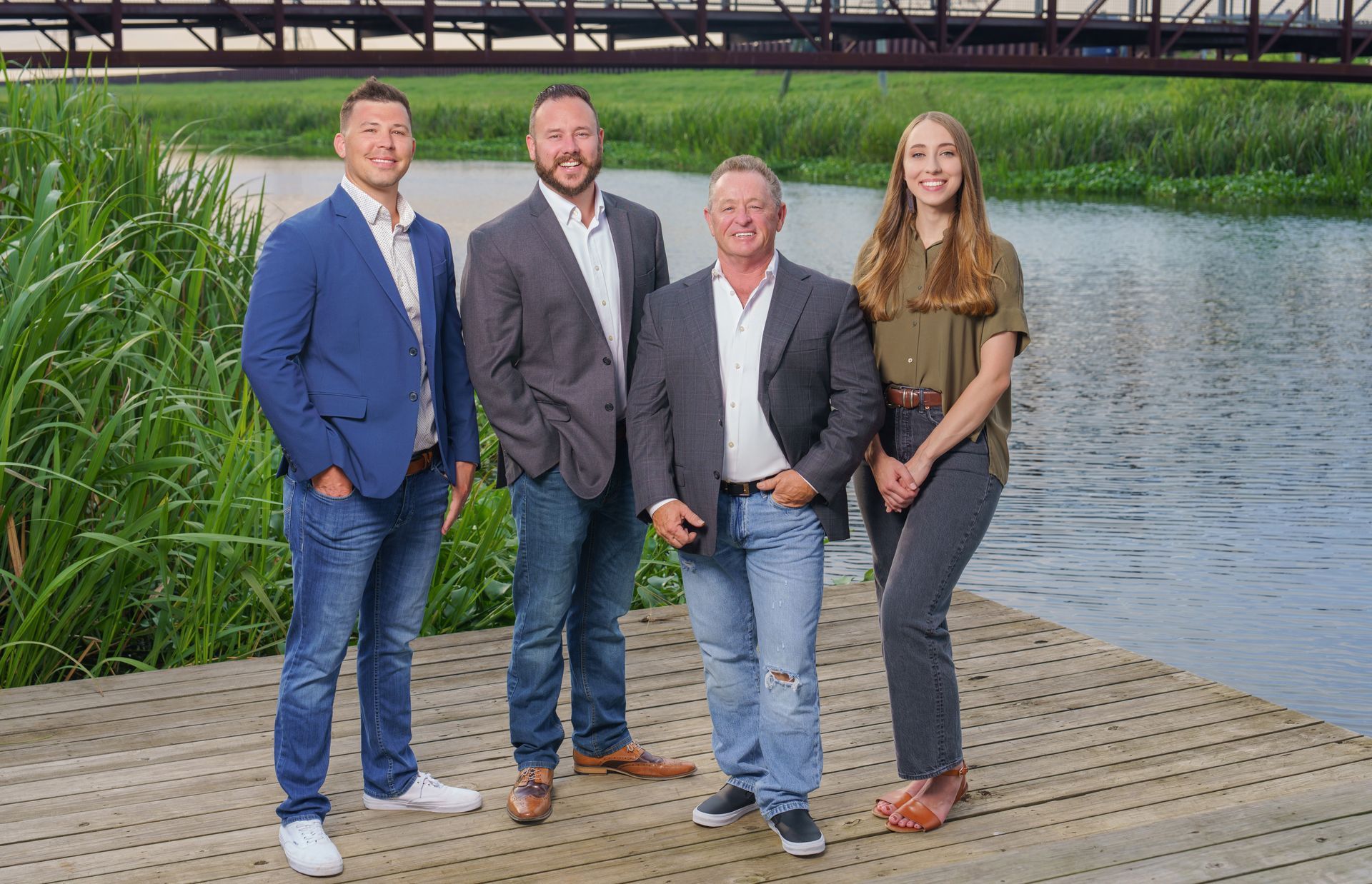 A group of people are standing on a dock next to a body of water.