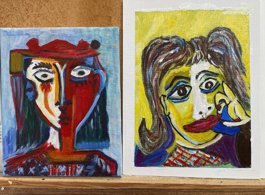 Two colorful abstract portrait paintings side by side on a corkboard background