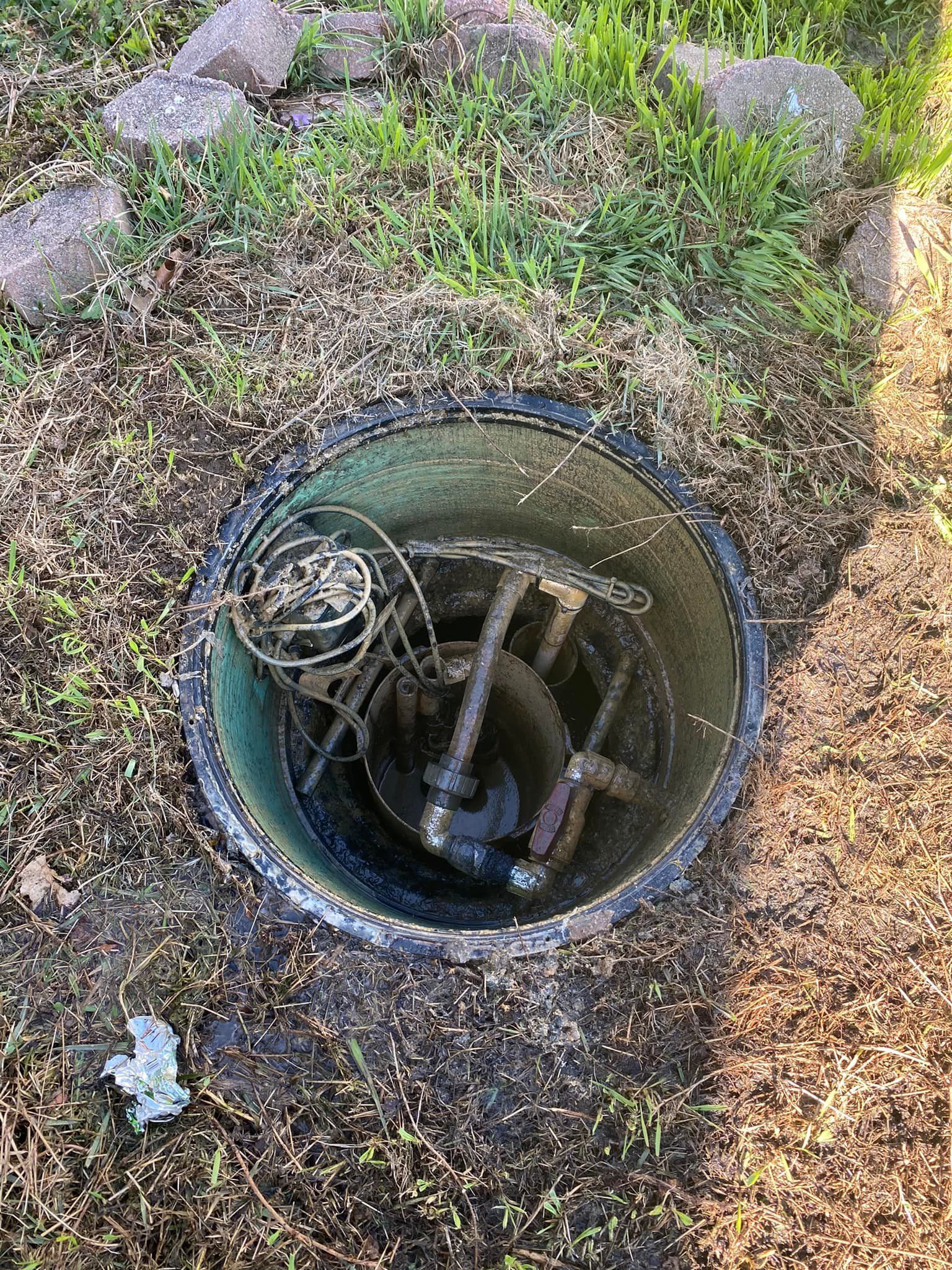 A hole in the ground with a hose in it.