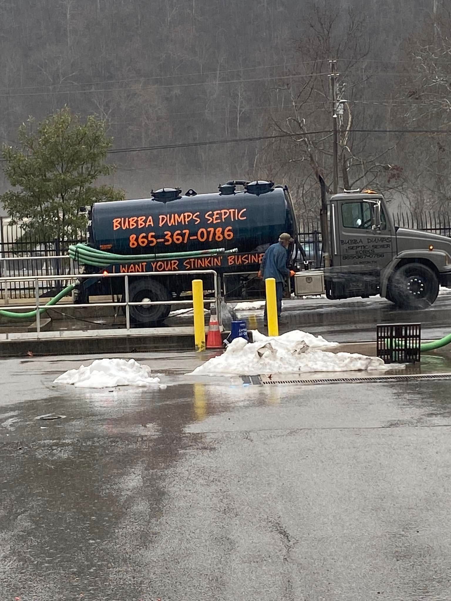 A tanker truck is parked in a parking lot with a man standing next to it.