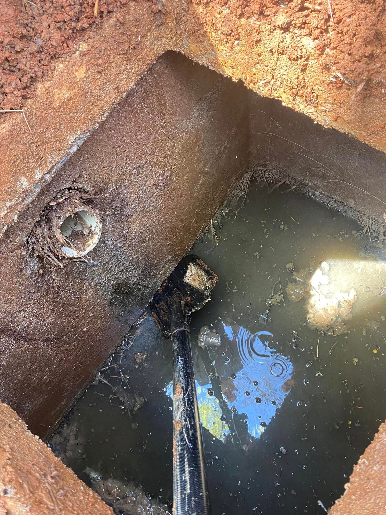 A hole in the ground filled with water and a shovel in it.