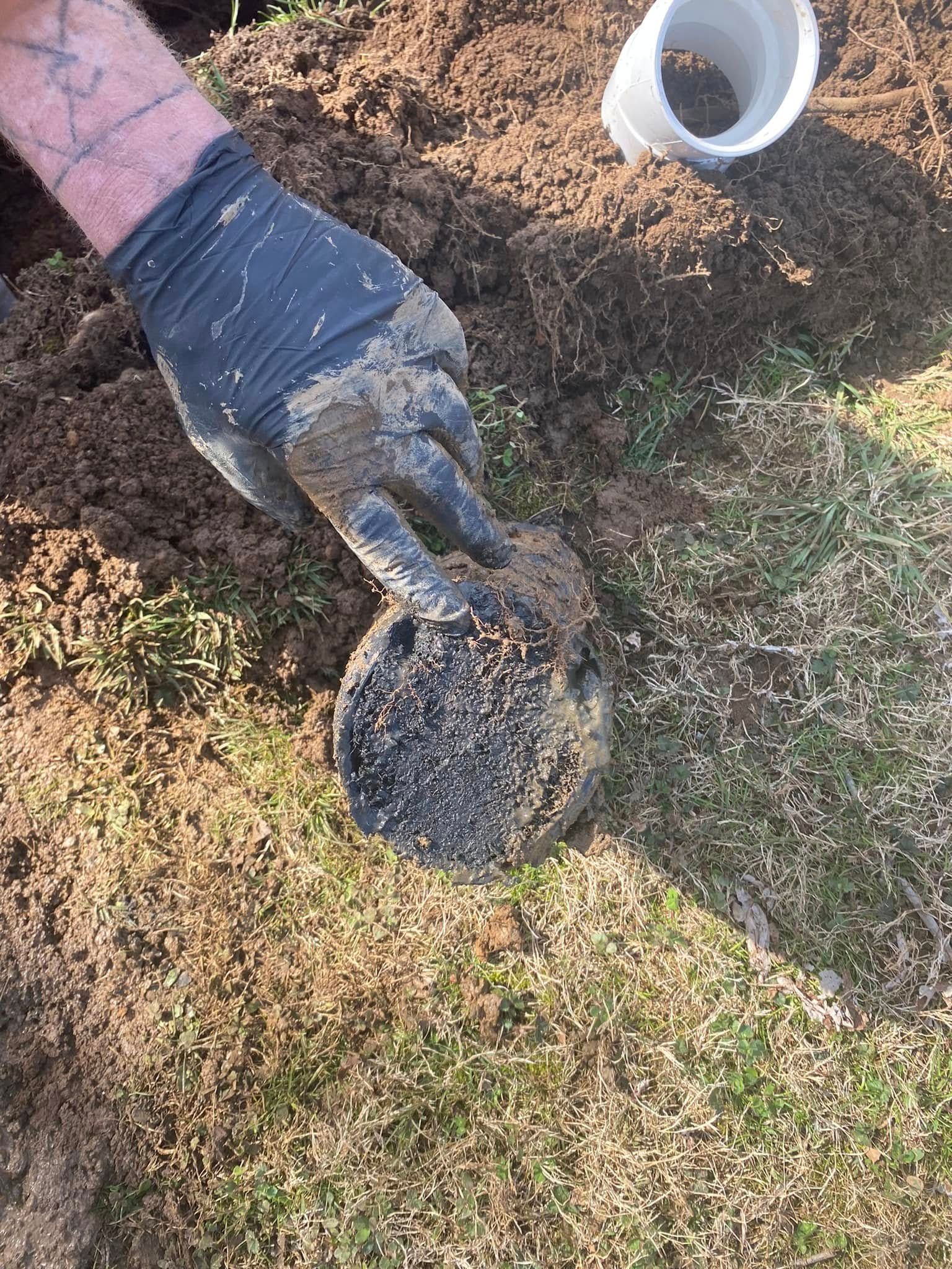 A person wearing gloves is digging in the dirt with a shovel.
