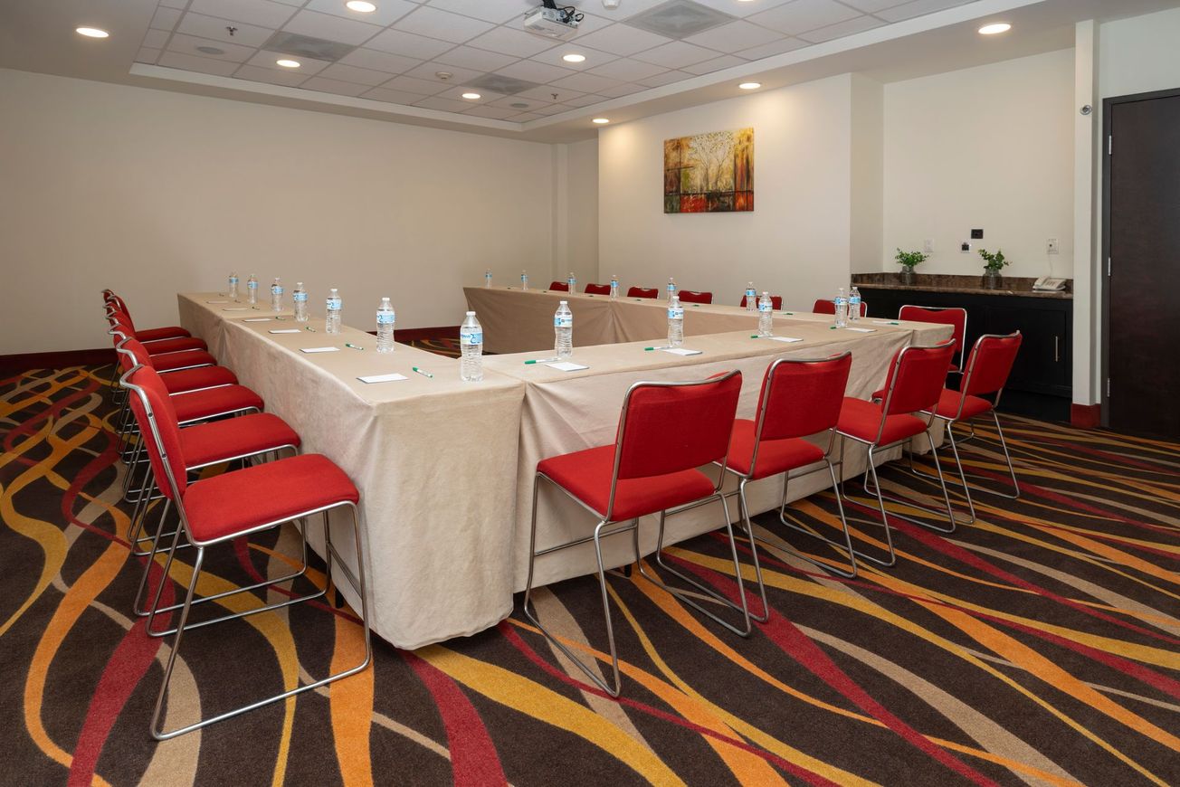 Una sala de conferencias con una mesa larga y sillas rojas.