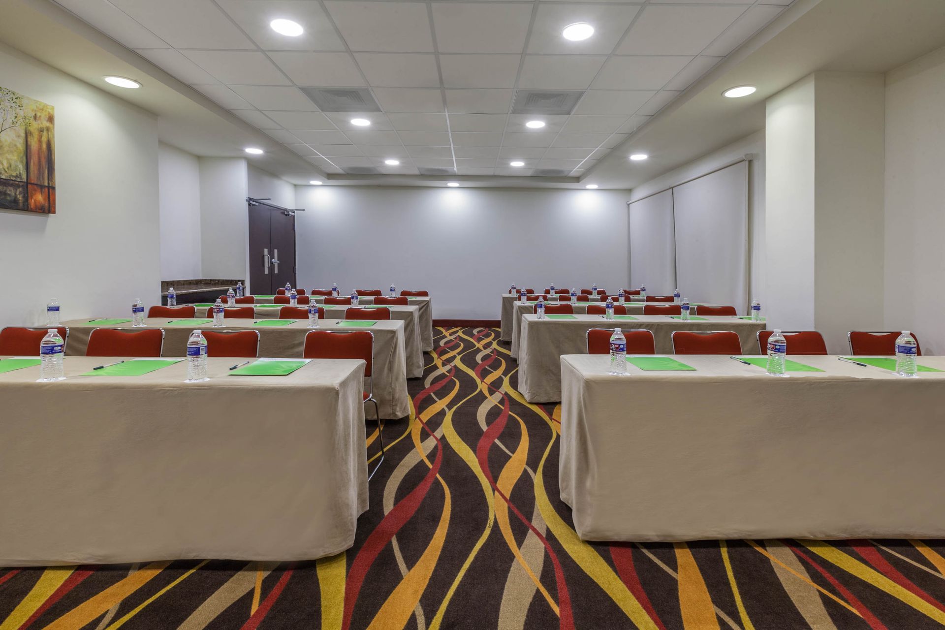 Una sala de conferencias con largas mesas y sillas y una alfombra colorida.