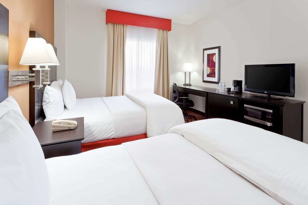 Una habitación de hotel con dos camas y un televisor de pantalla plana.