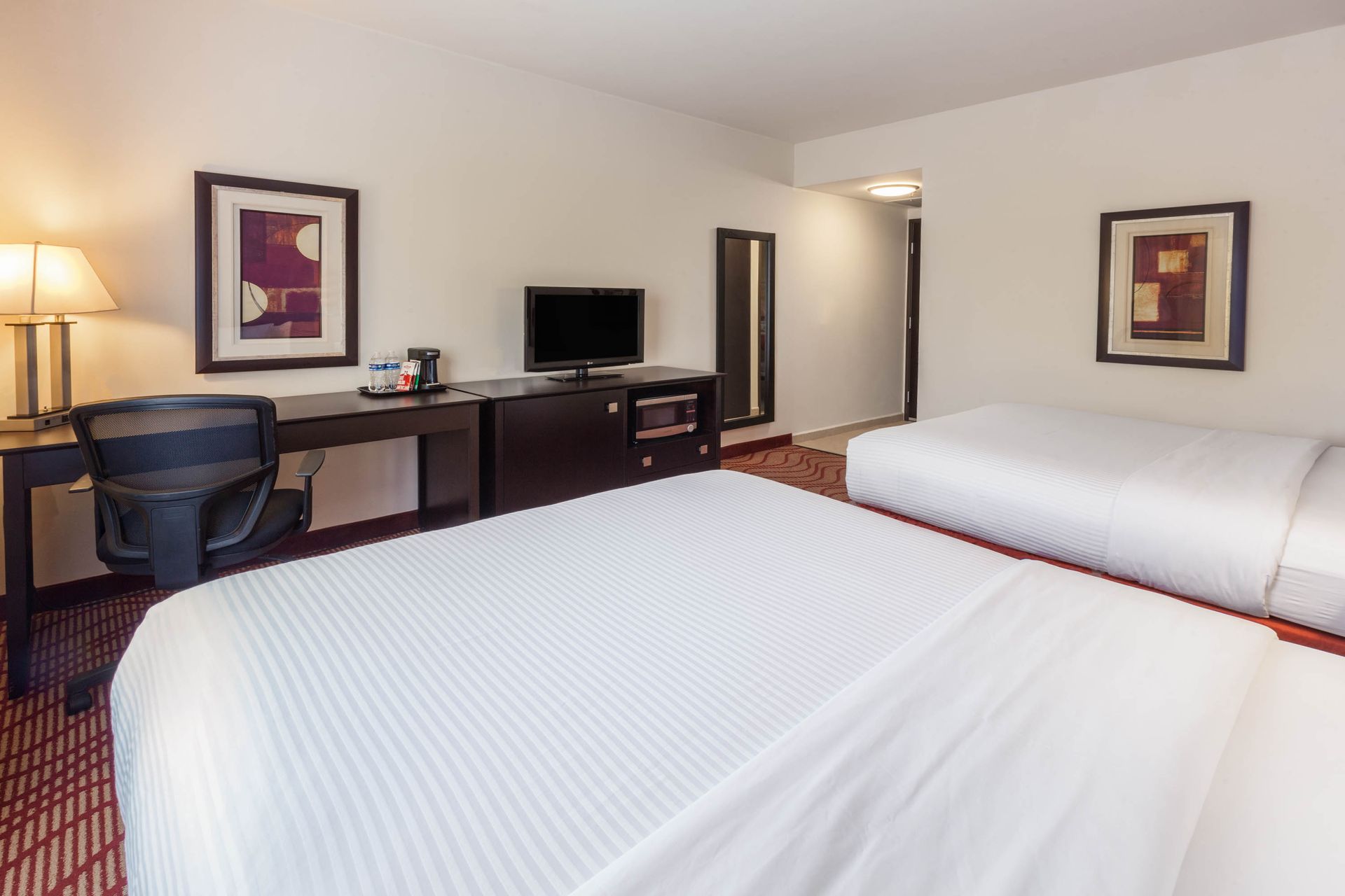 Una habitación de hotel con dos camas, un escritorio y una televisión.