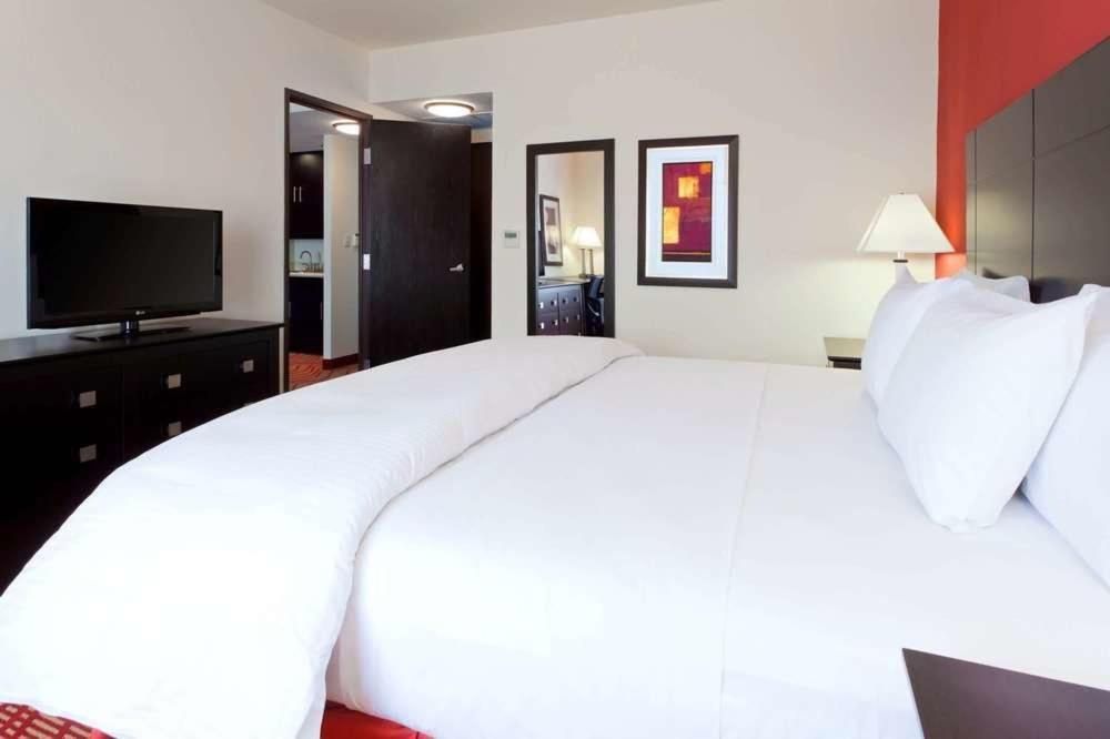 Una habitación de hotel con una cama tamaño king y un televisor de pantalla plana.