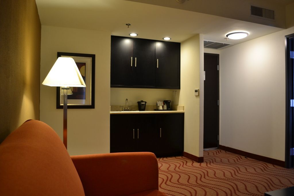 Una habitación de hotel con un sofá y una lámpara.