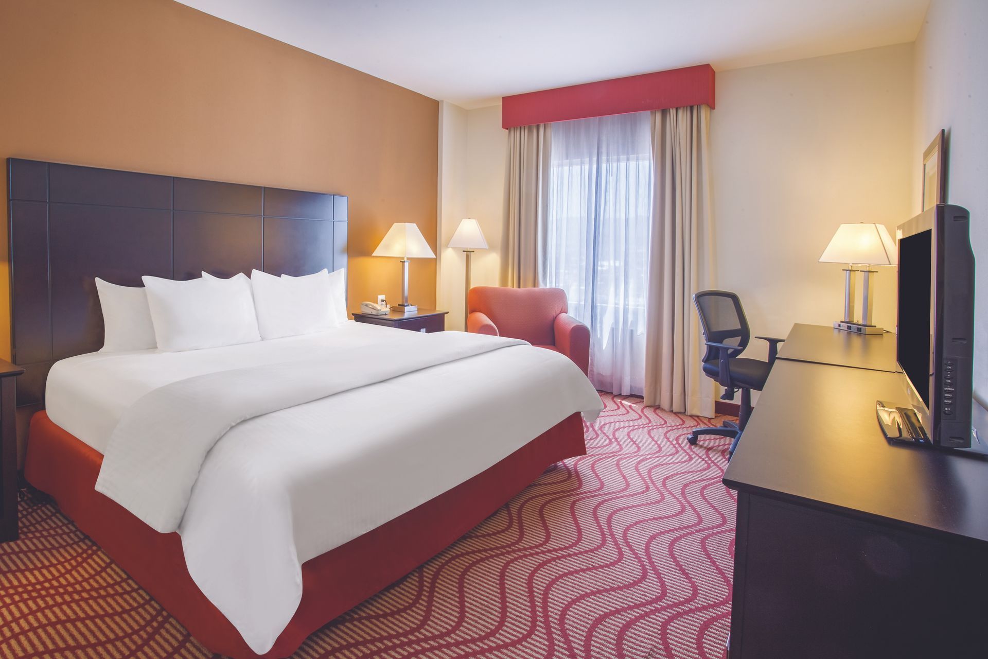 Una habitación de hotel con una cama tamaño king y un escritorio.