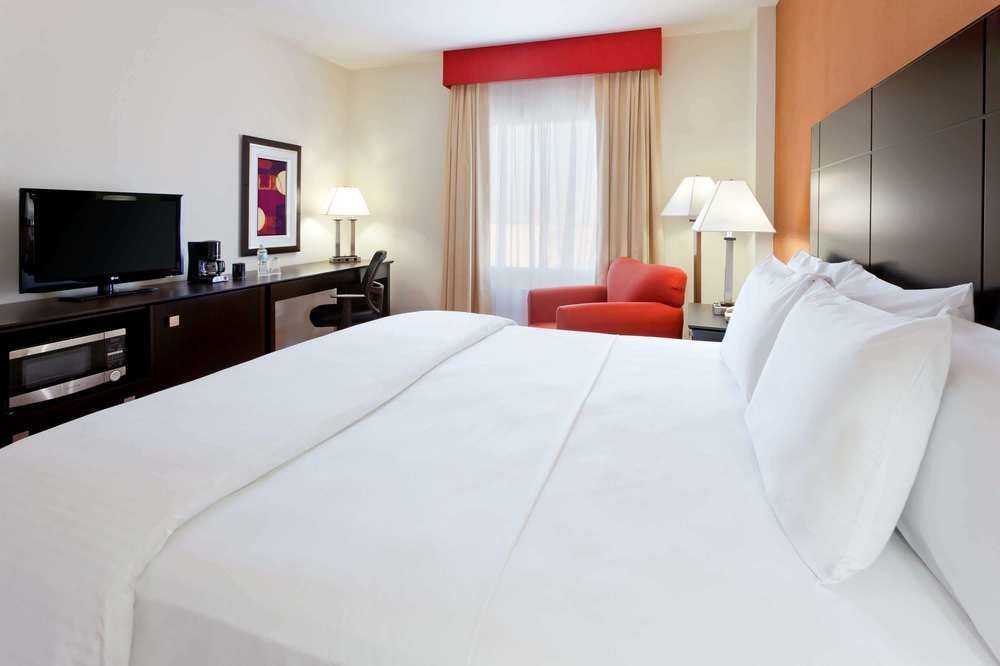 Una habitación de hotel con una cama tamaño king y un televisor de pantalla plana.