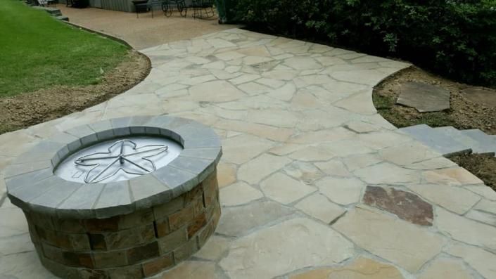 Stone patio path with a circular built-in fire pit in a landscaped yard
