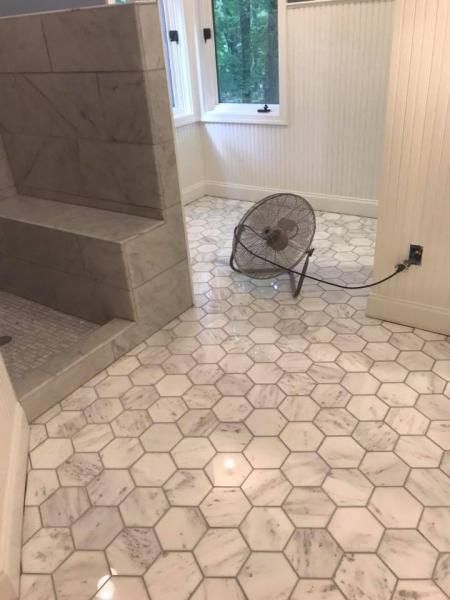Small room with hexagon tile floor, built-in gray seating, window, and a floor fan near an outlet.