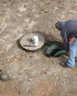 A man is working on a septic tank in the dirt.