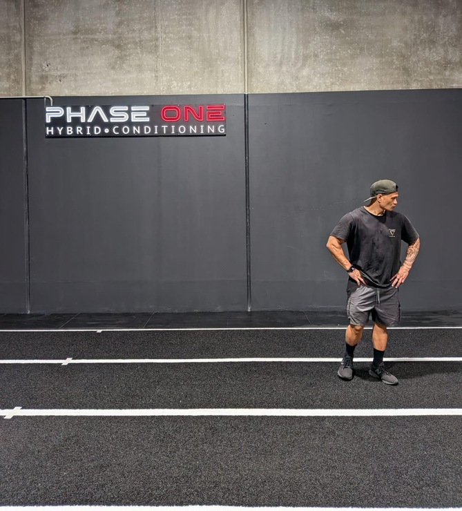 Man in gym attire preparing to deadlift a barbell with weights.