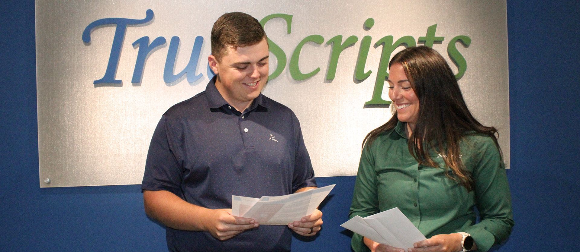 Two TrueScripts employees smiling while reviewing documents