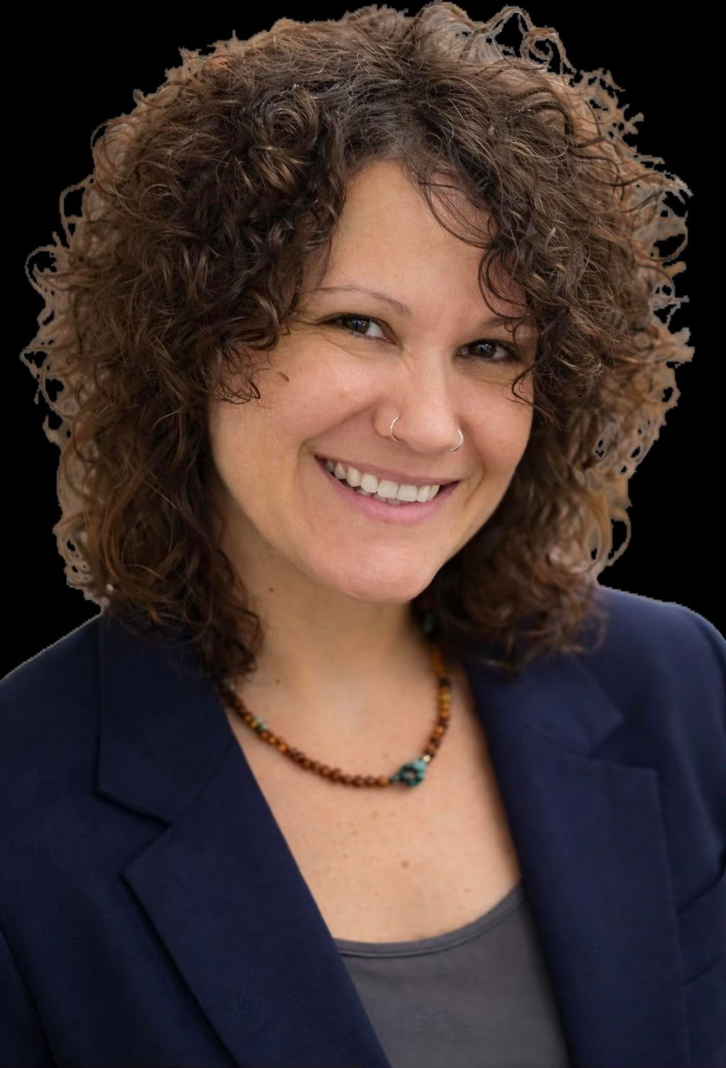 Smiling woman with curly hair in a navy blazer and necklace on a black background