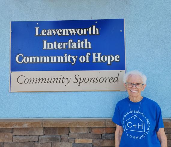 Leavenworth Interfaith Community of Hope sign beside smiling woman in blue shirt