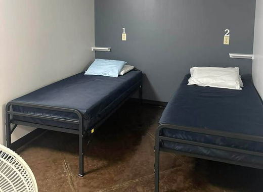 Small room with two single beds, dark blue bedding, and wall-mounted number signs 1 and 2.