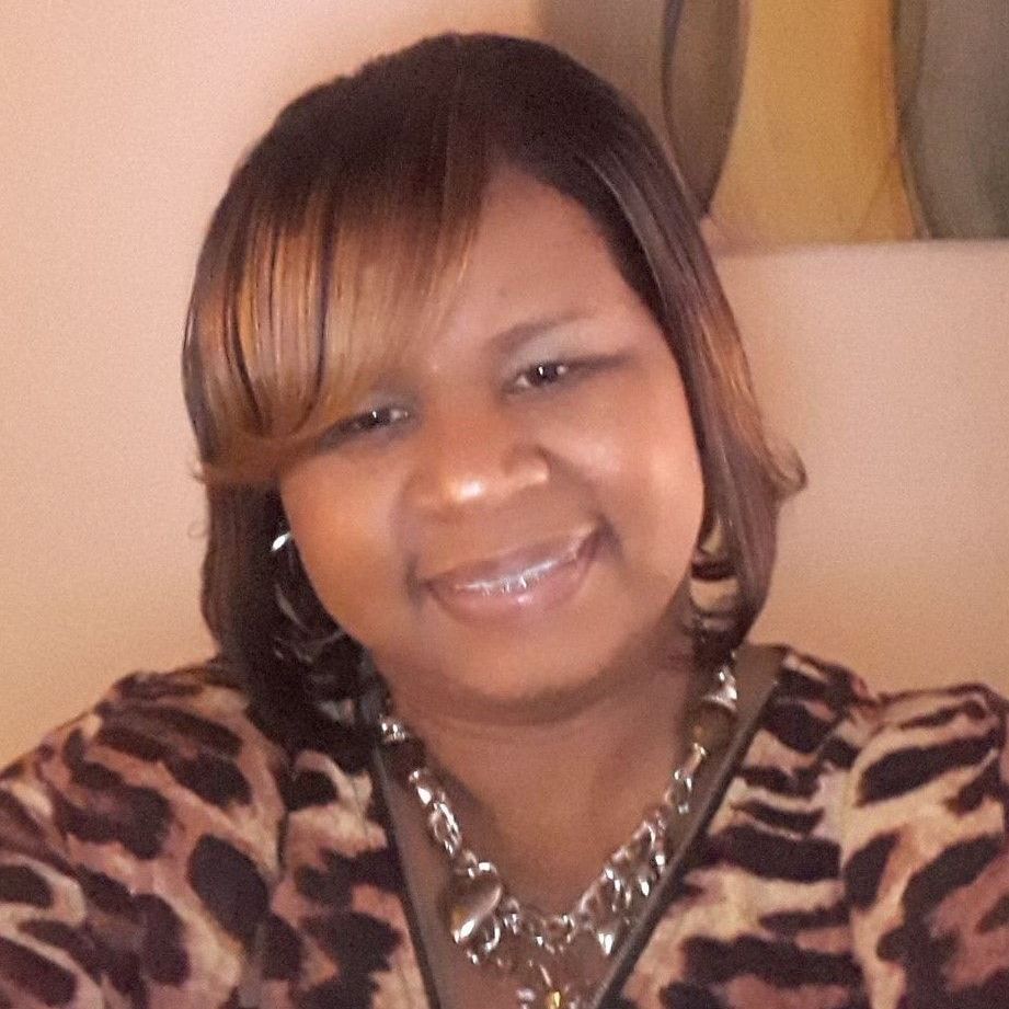 A woman wearing a leopard print shirt and a necklace is smiling for the camera.
