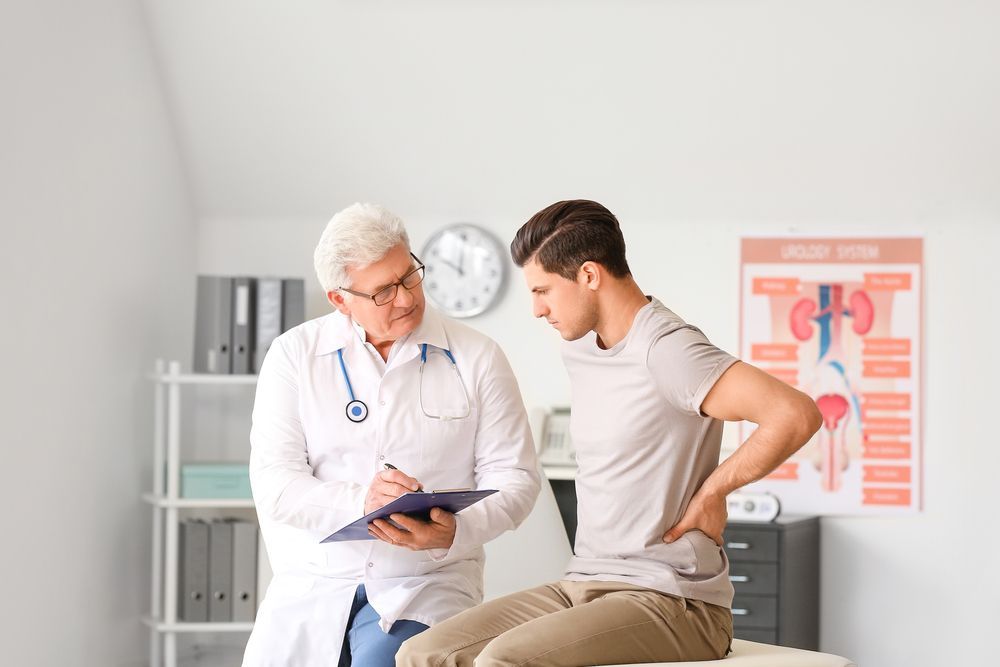 A doctor is talking to a patient who is sitting on a bed.