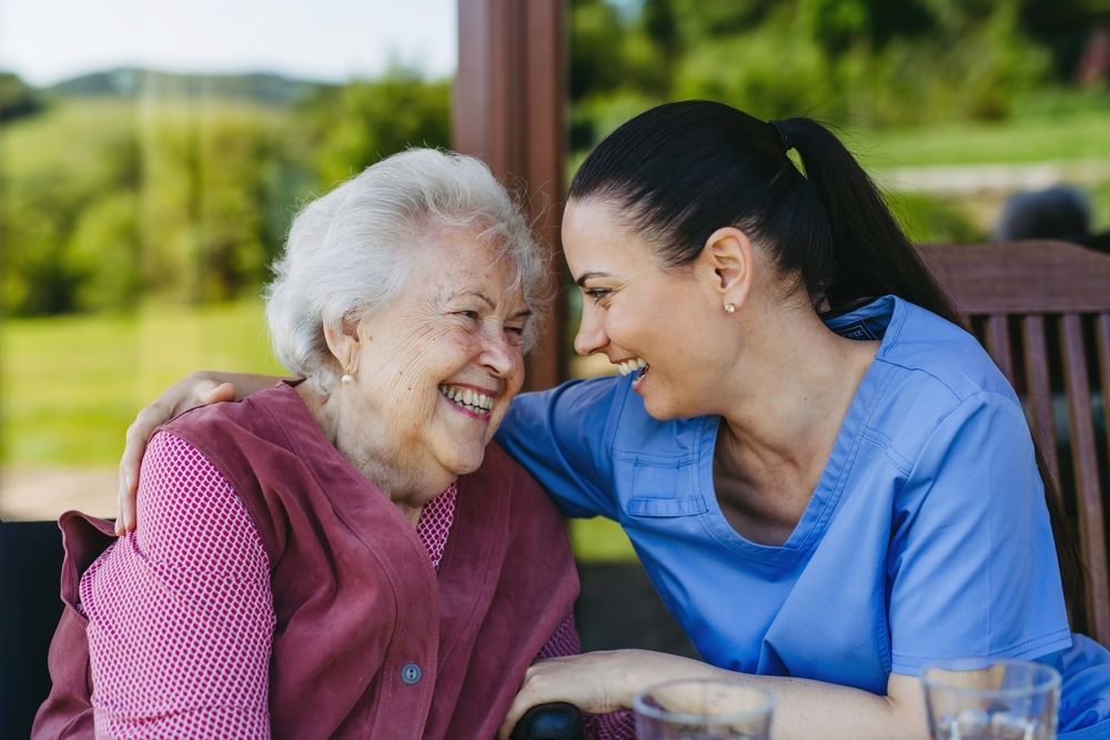 An elderly woman is sitting next to a younger woman on a porch.