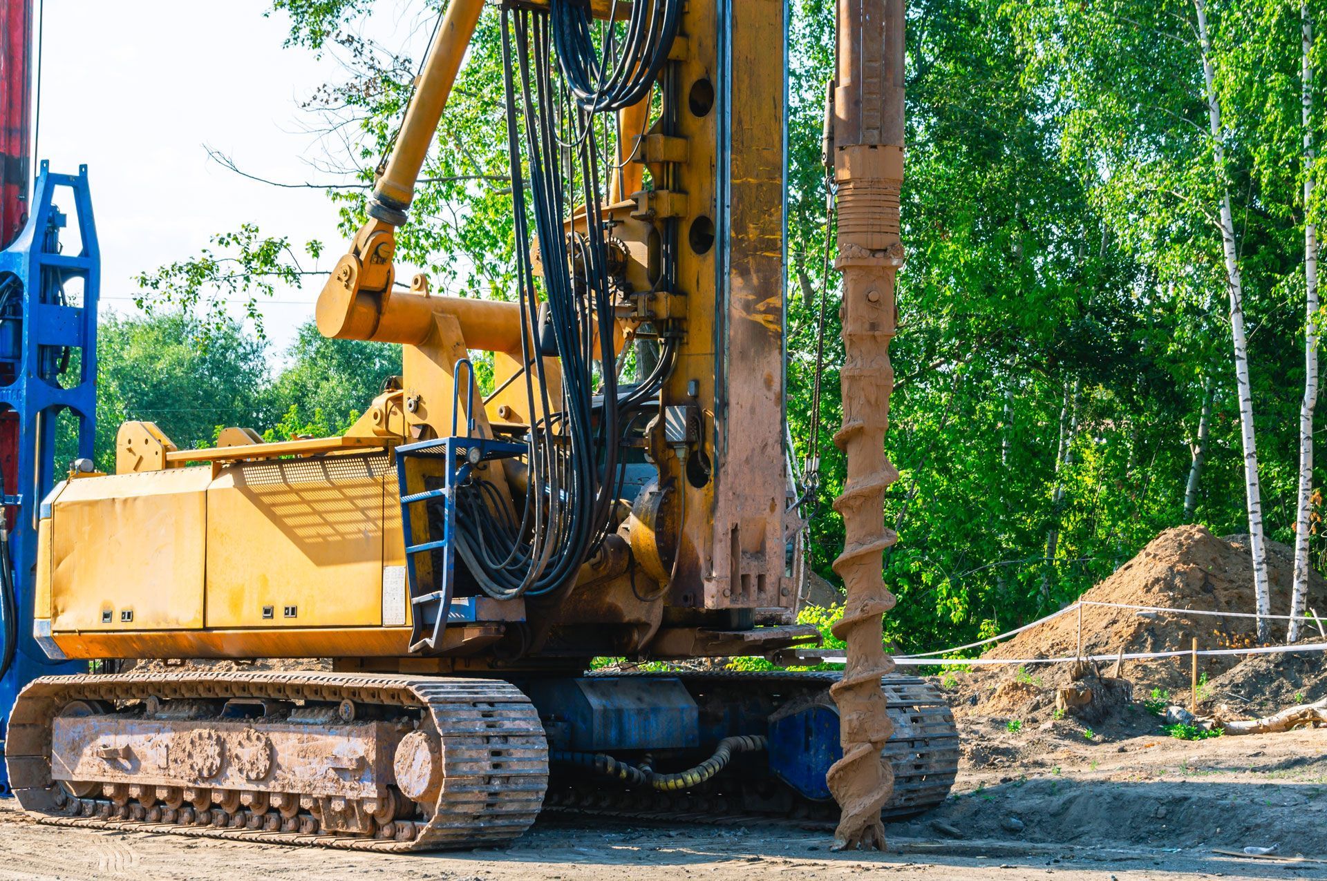 Yellow excavator on a dirt site with trees in the background