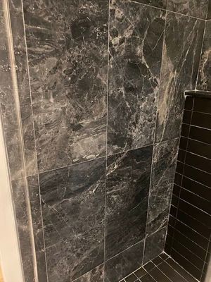 Dark gray marble-look shower wall tiles with a narrow black tiled corner