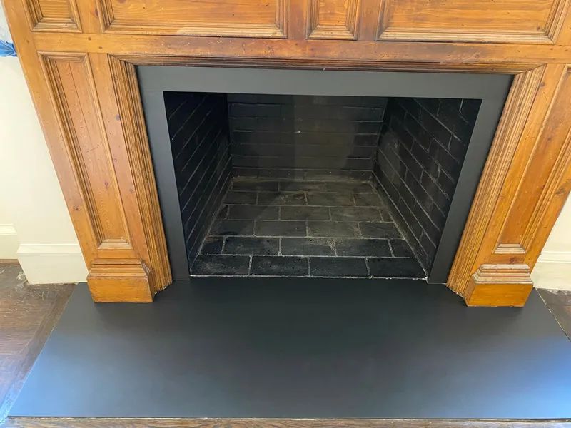 Black fireplace opening framed by wood cabinets above a dark hearth floor.