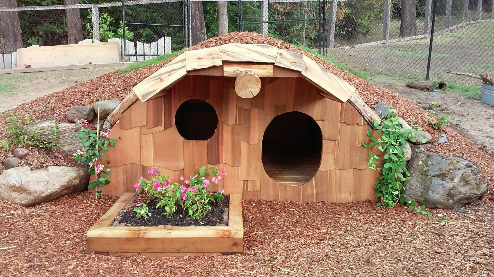 A small wooden house with flowers in front of it
