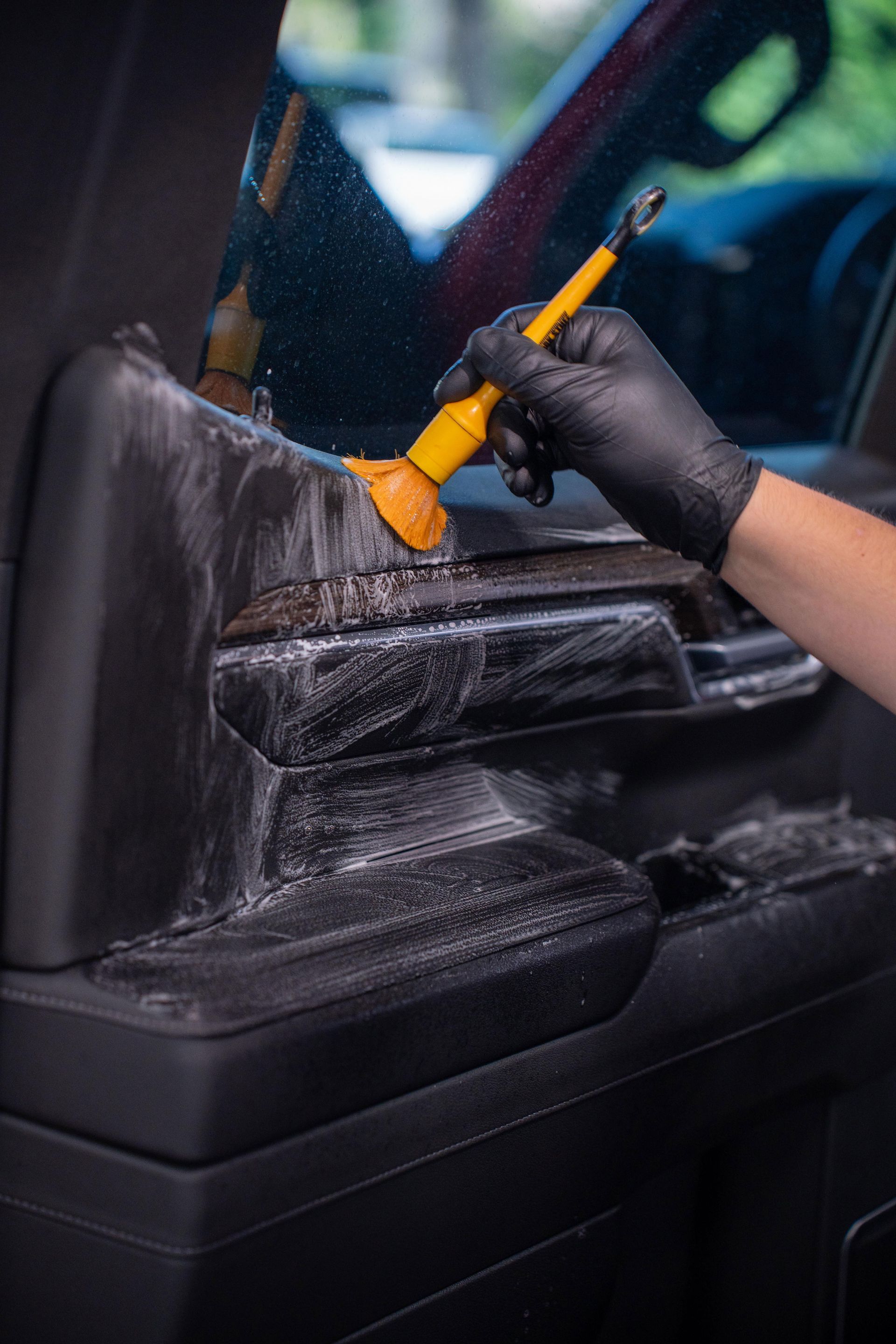 A person is cleaning the interior of a car with a brush.