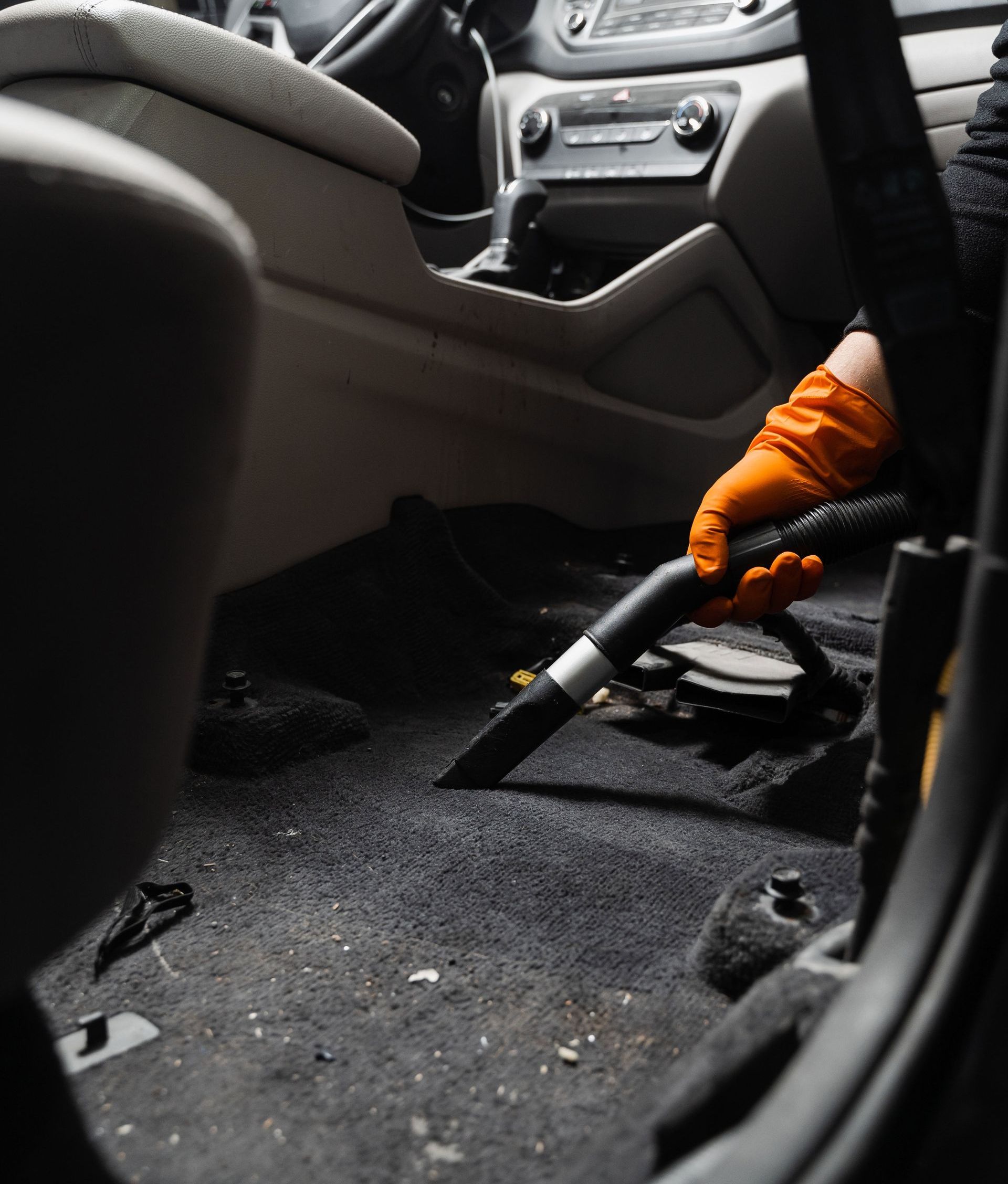A person is using a vacuum cleaner to clean the floor of a car.