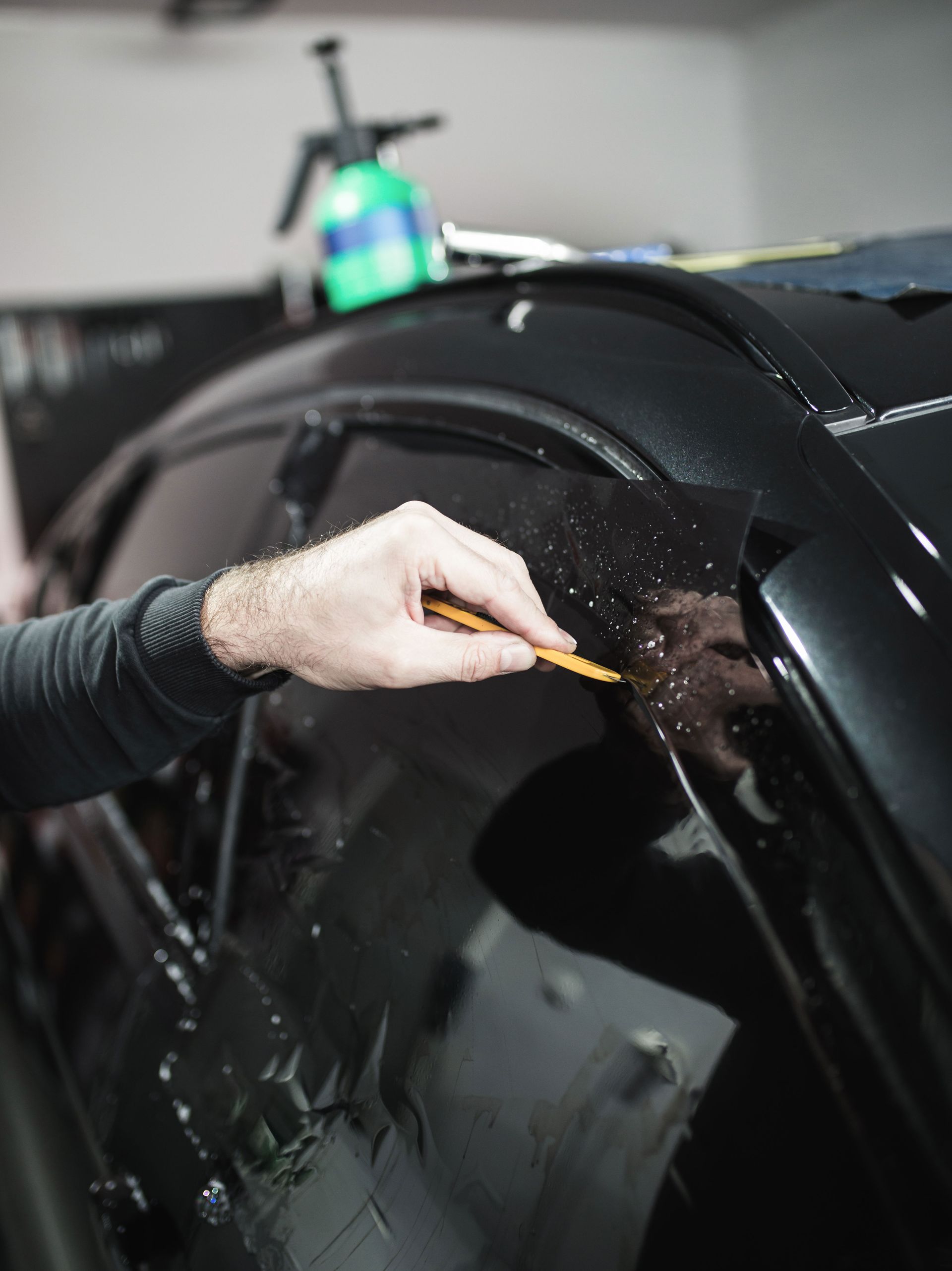 A man is applying tinted glass to a car window.