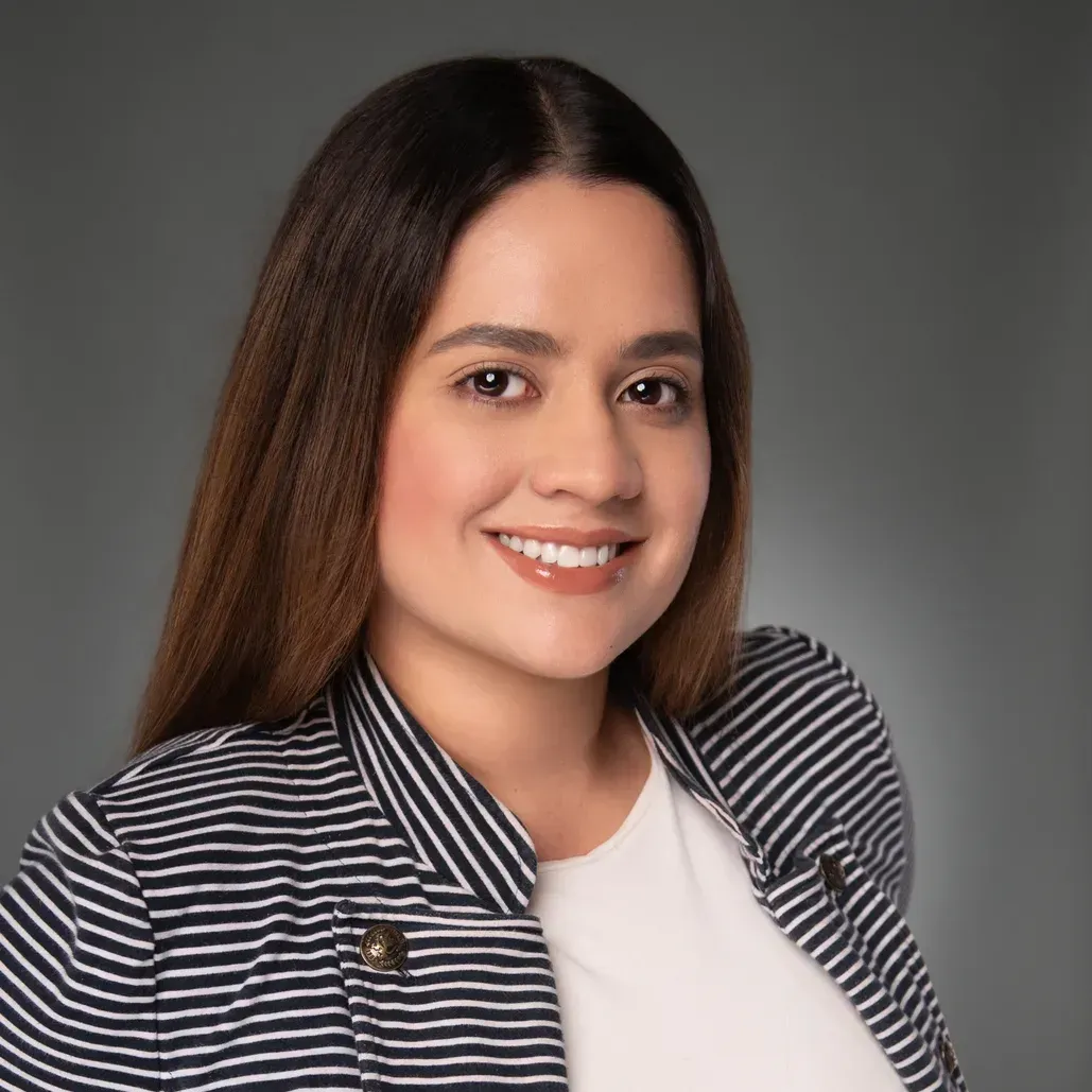 Smiling woman in a striped blazer and white top against a gray background